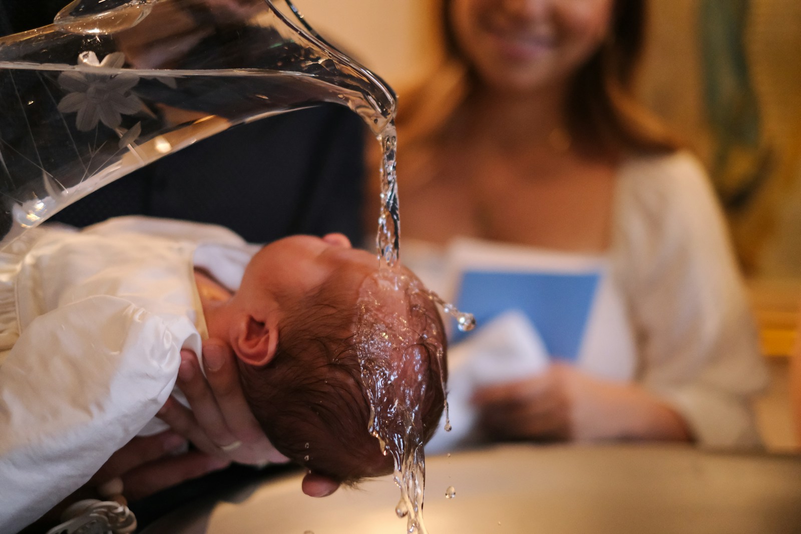 Taufbecken mit Wasser über dem Kopf eines Säuglings
